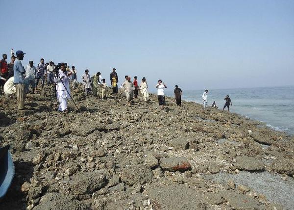 Members of the media and people walk on an island that rose from the sea following an earthquake off Pakistan's Gwadar coastline in the Arabian Sea